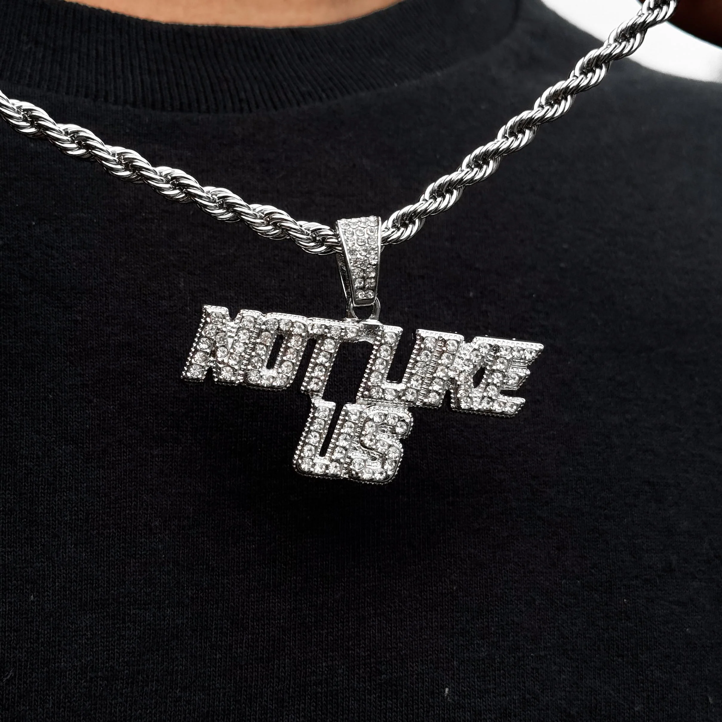 Silver iced out “Not Like Us” pendant on 4mm rope chain for men, bold hip hop jewelry style.