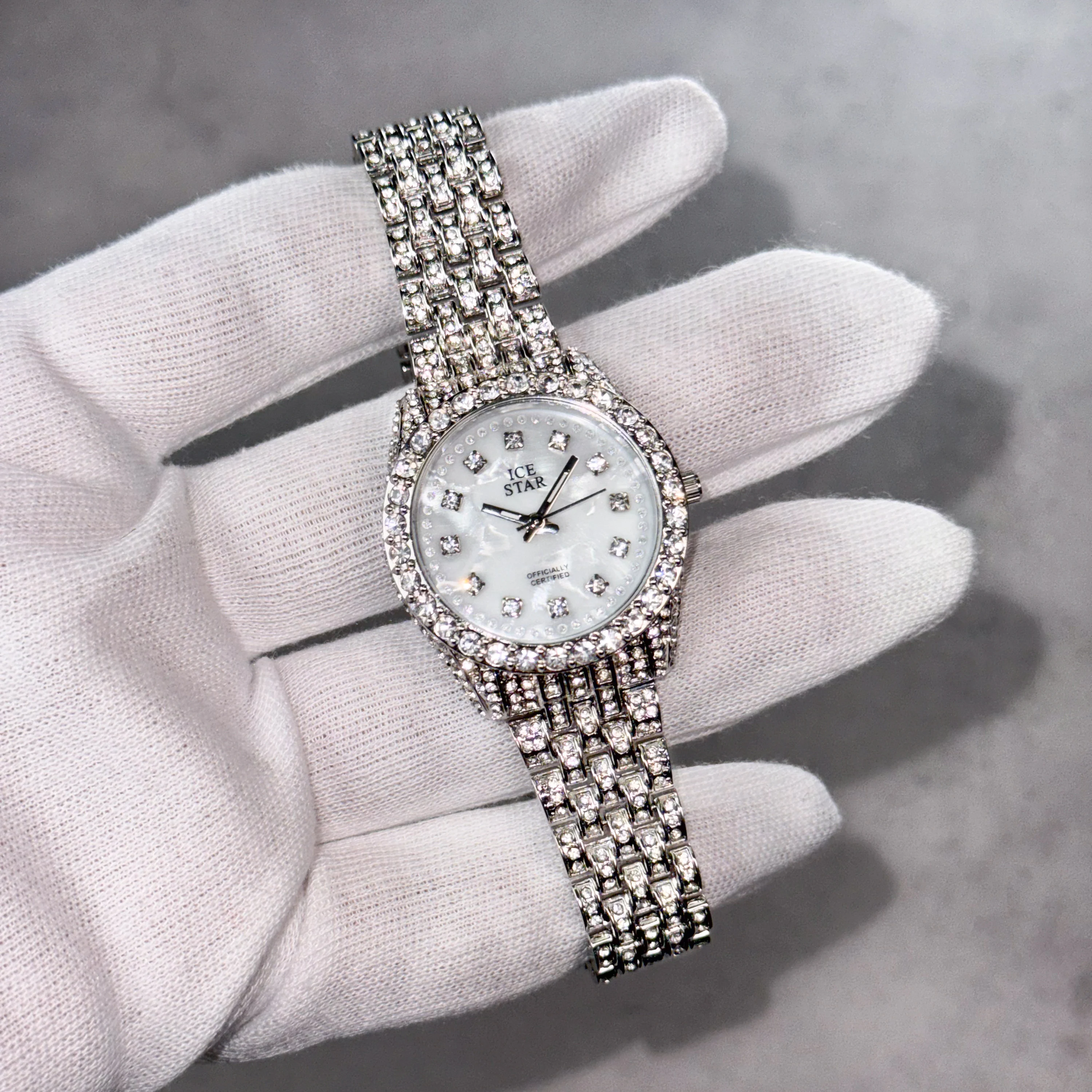 Women's 32mm silver diamond watch with mother-of-pearl dial and fully iced crystal bezel.