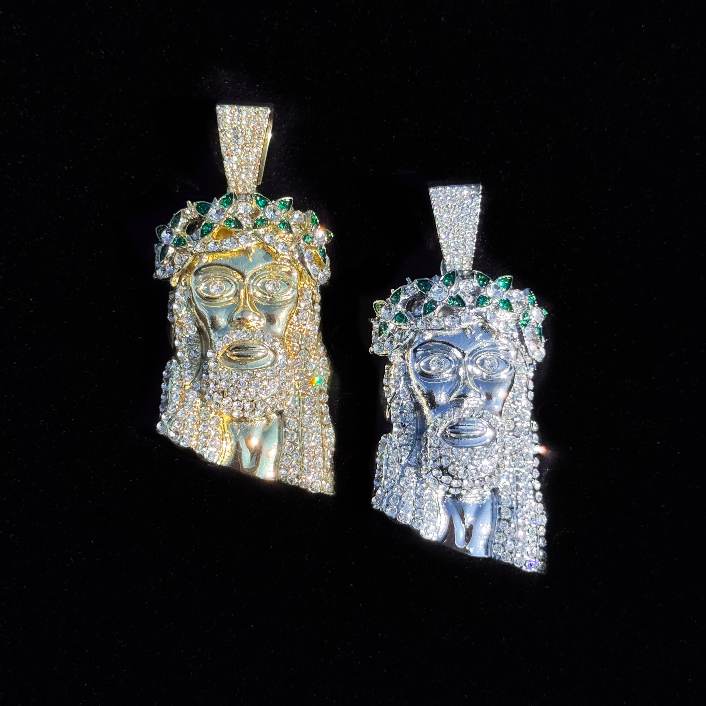 Gold and silver iced-out Jesus spiked crown pendant with green stones displayed in hand for detail view.