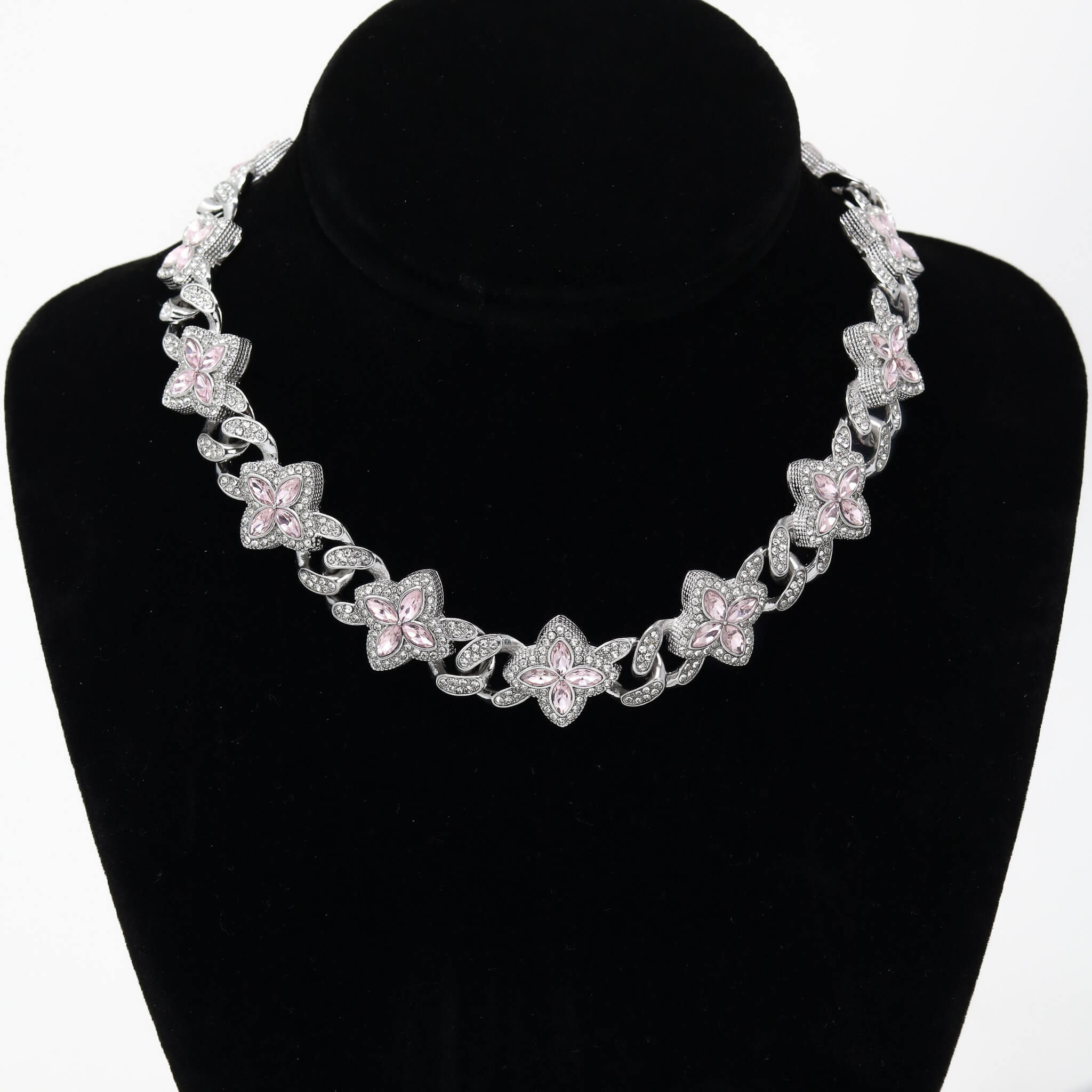 Iced Clover Cuban Chain with pink stones and silver detailing displayed on a black jewelry stand.