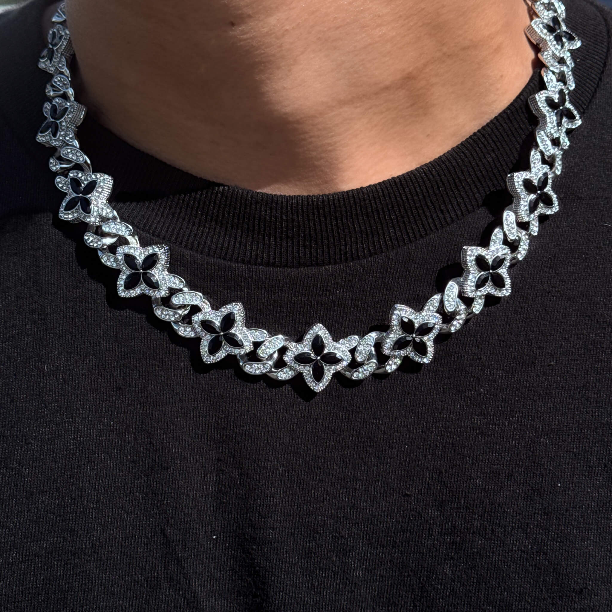 Iced Clover Cuban Chain with black stones on silver links, worn on neck for a bold iced look.