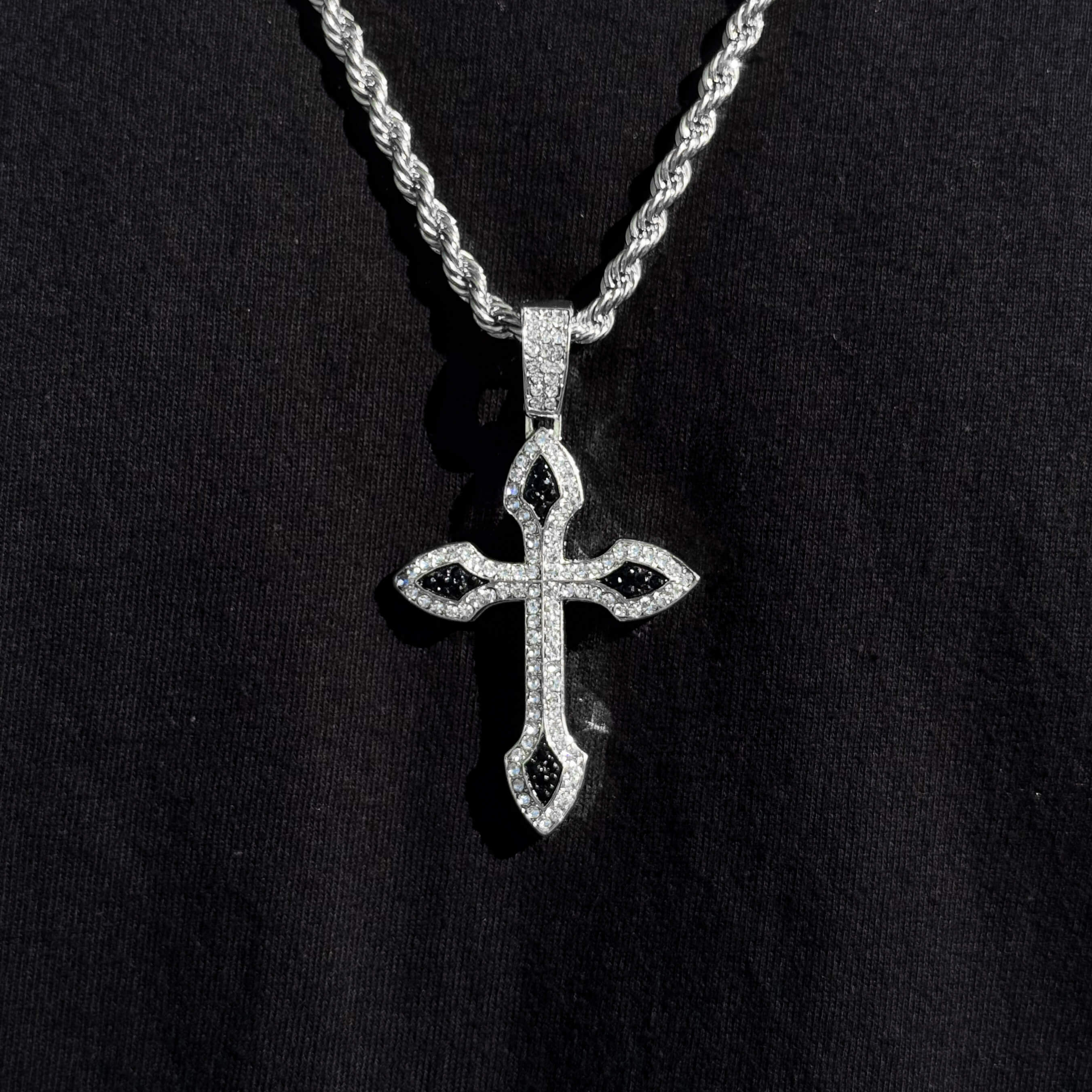 Men's large iced-out cross pendant in silver with rope chain, featuring black gemstone accents.
