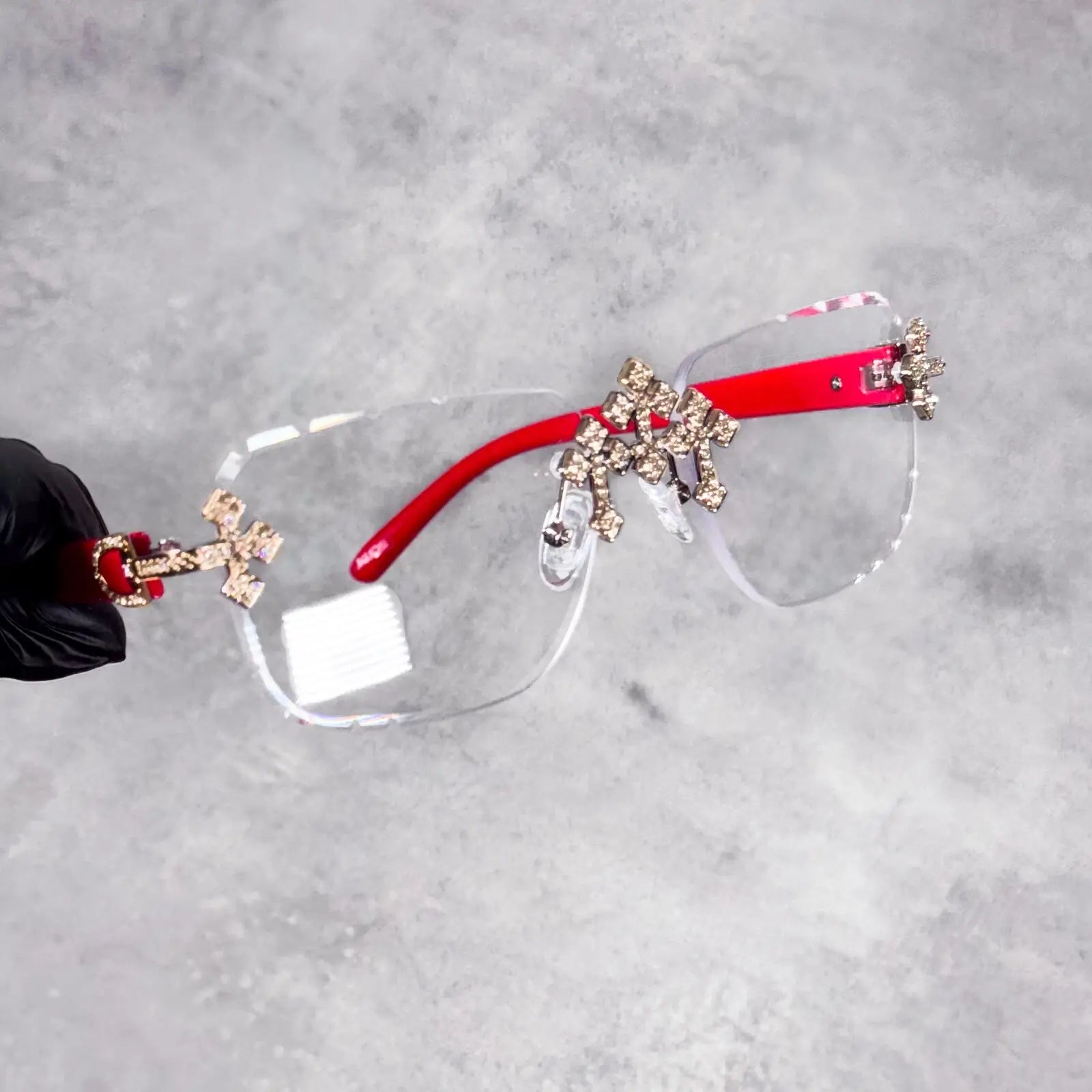Rimless clear Iced Triple Cross Sunglasses showcasing red arms and diamond-cut cross hardware.