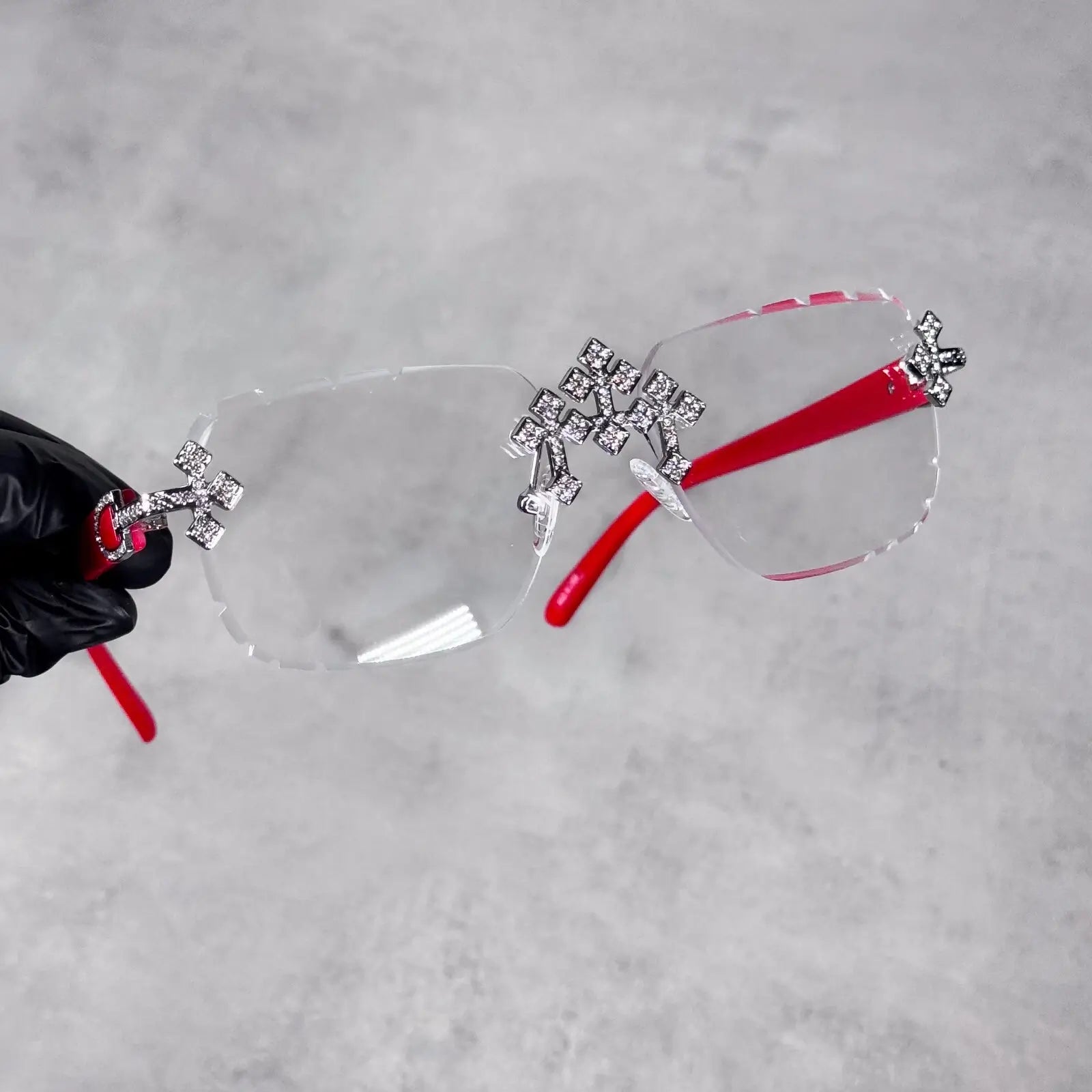 Rimless clear Iced Triple Cross Sunglasses featuring bright red temples and jeweled cross details.