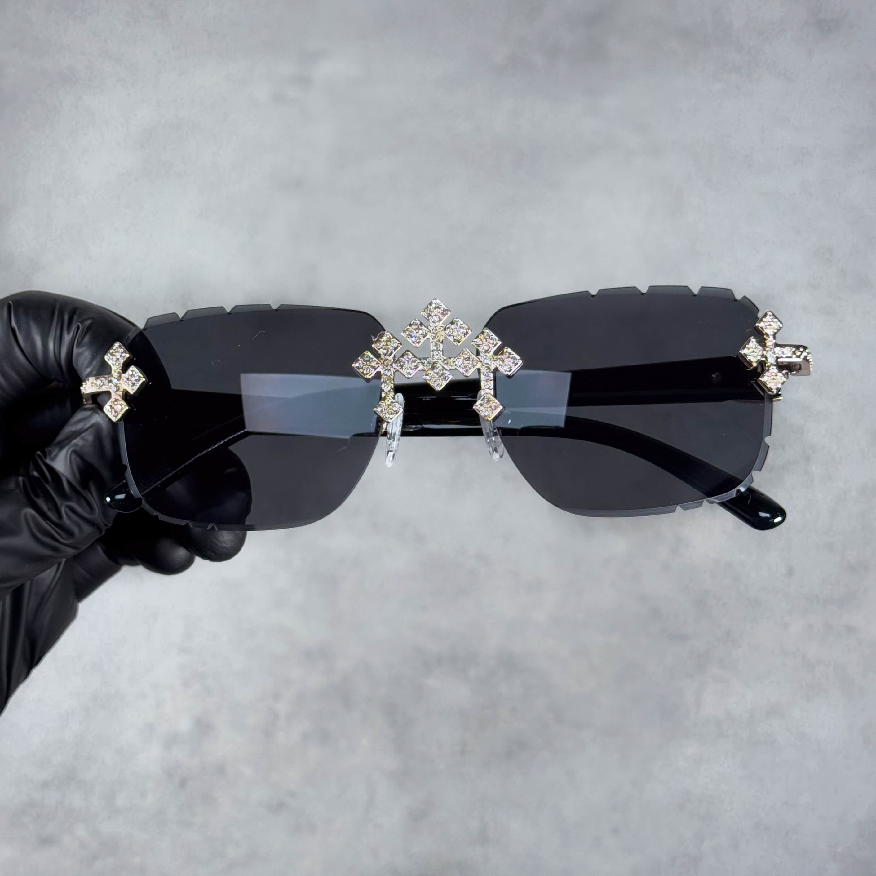 Black lens iced triple cross sunglasses with silver rhinestone accents and rimless design.