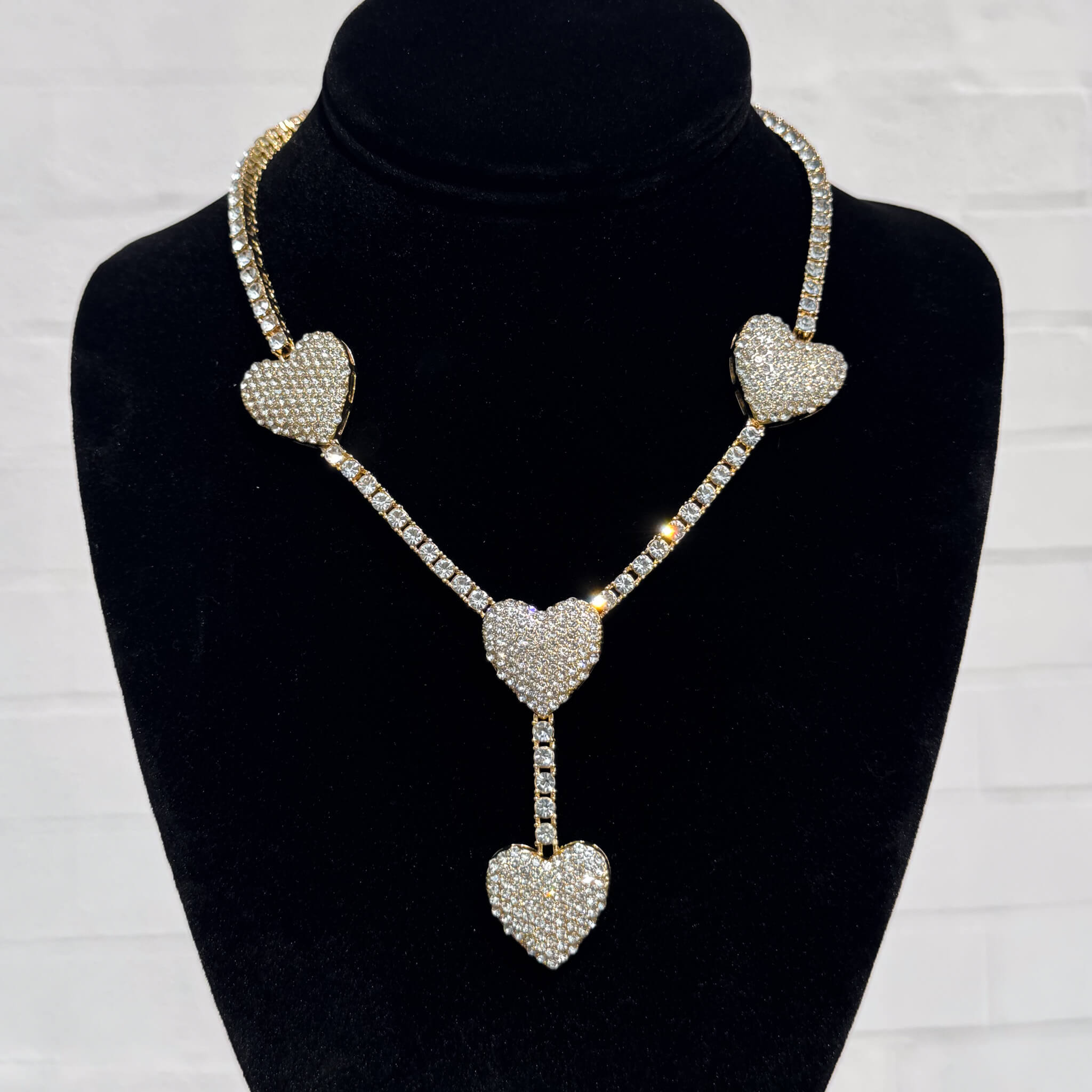 Iced Heart Lariat Tennis Necklace in gold with pavé crystal hearts shown on black velvet display.