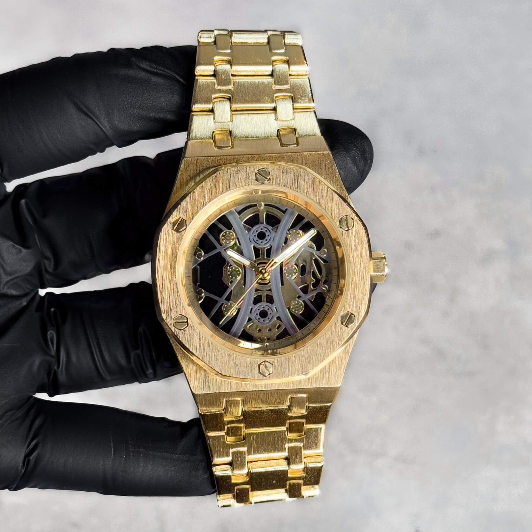 Men's 40mm gold luxury watch with octagon bezel, skeleton dial, and brushed metal bracelet.