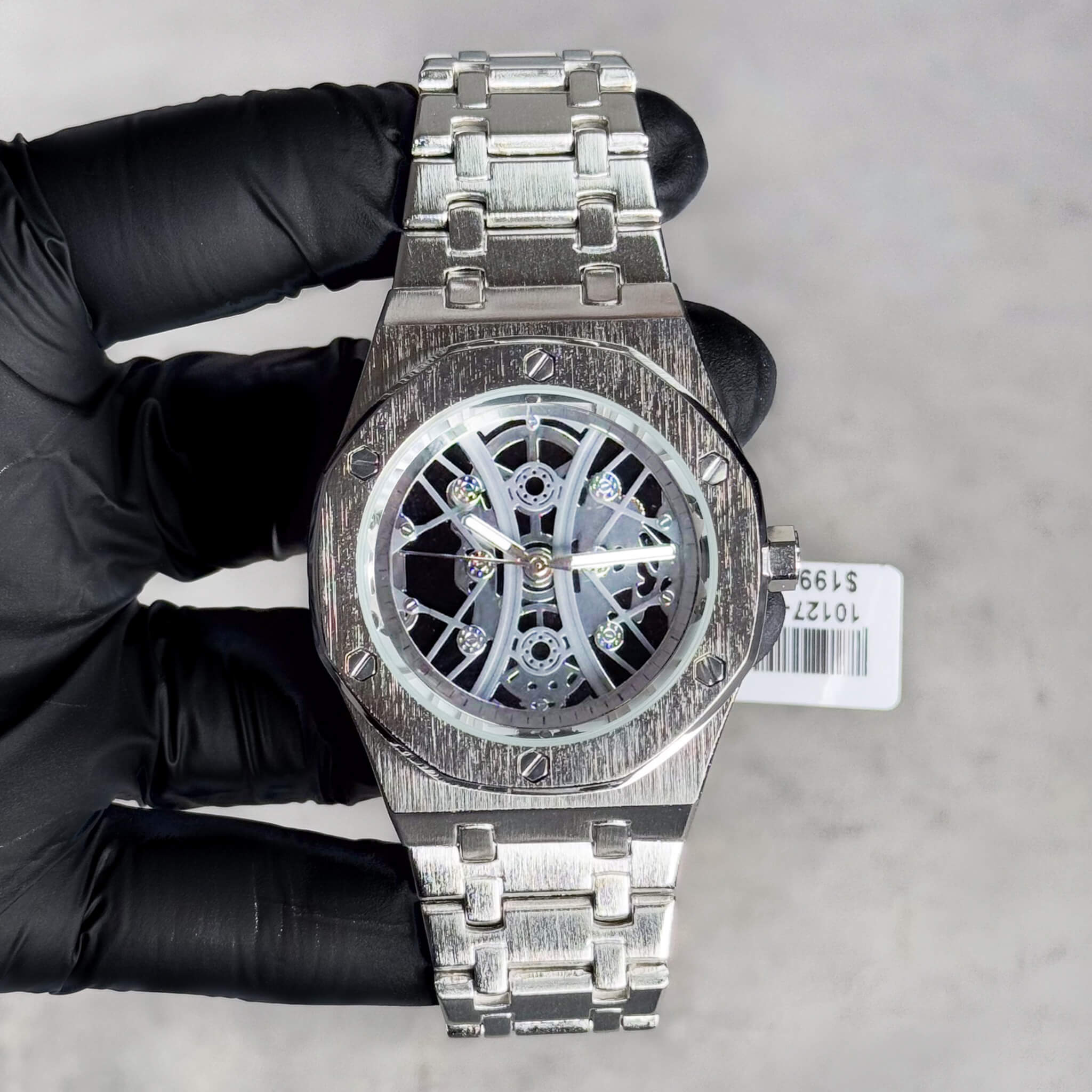 Men's 40mm silver octagon bezel skeleton watch featuring brushed metal band and open dial.