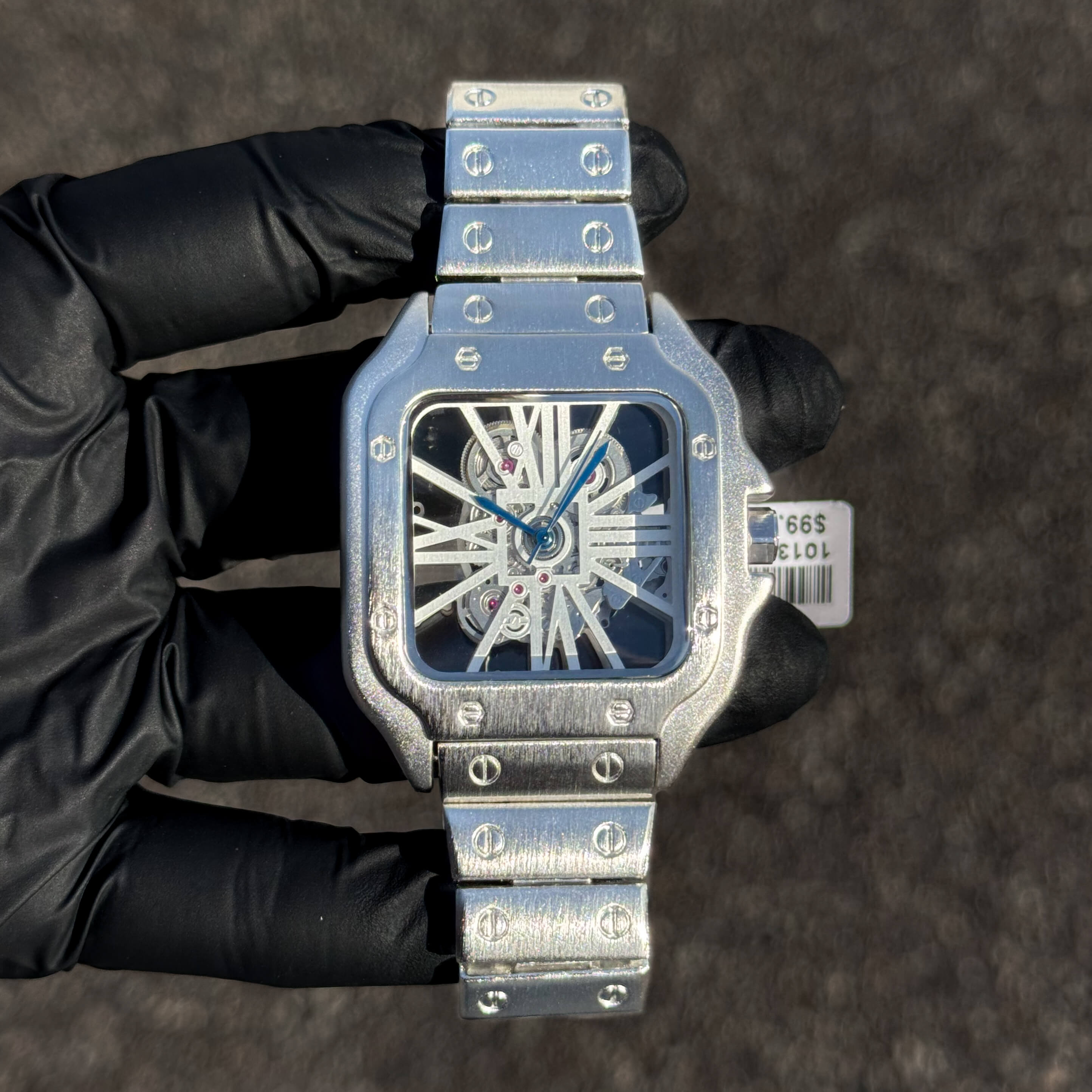 Men's 40mm silver square skeleton dial watch featuring brushed metal band and open-work design.