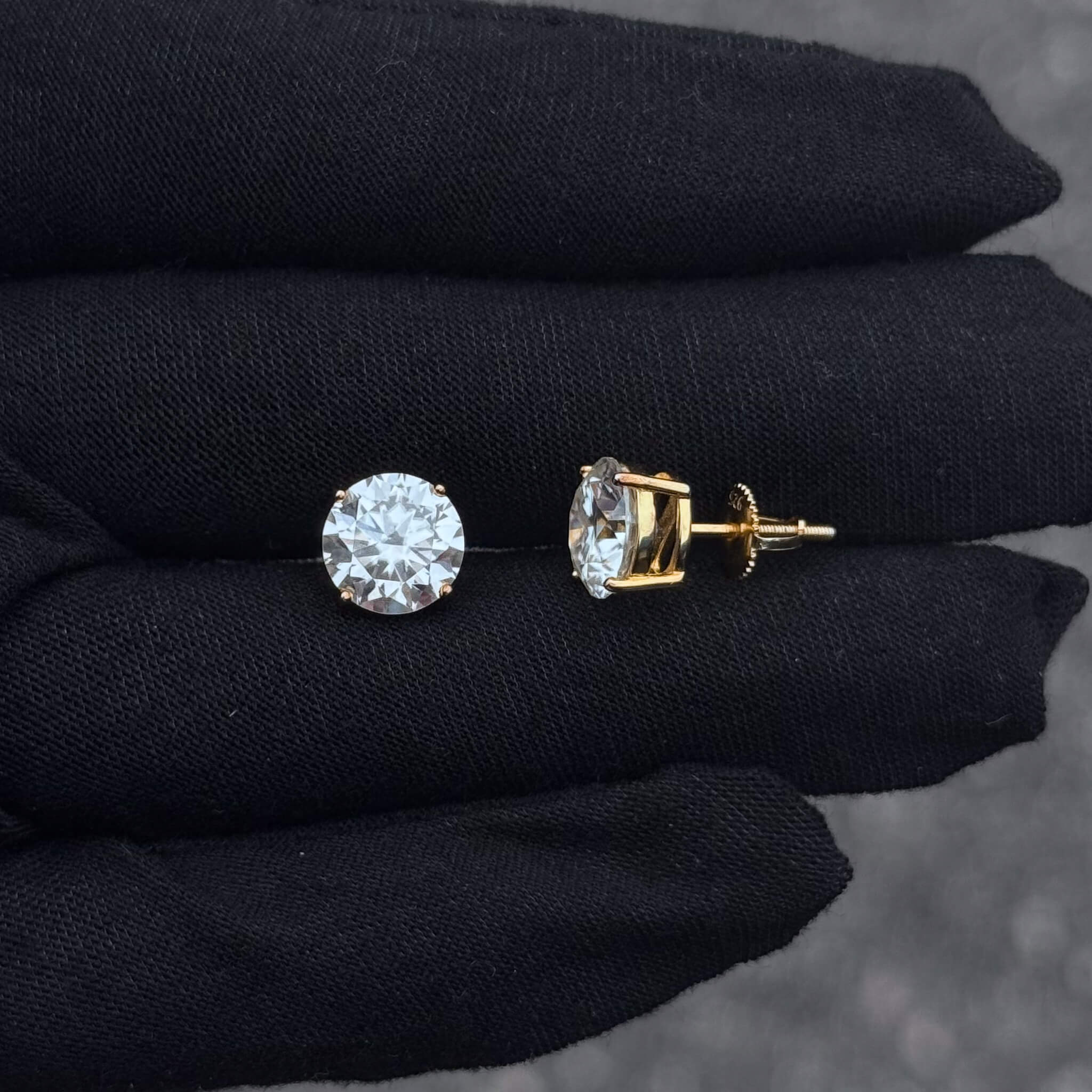 Side and front view of round moissanite solitaire earrings set in gold with secure screw-backs.