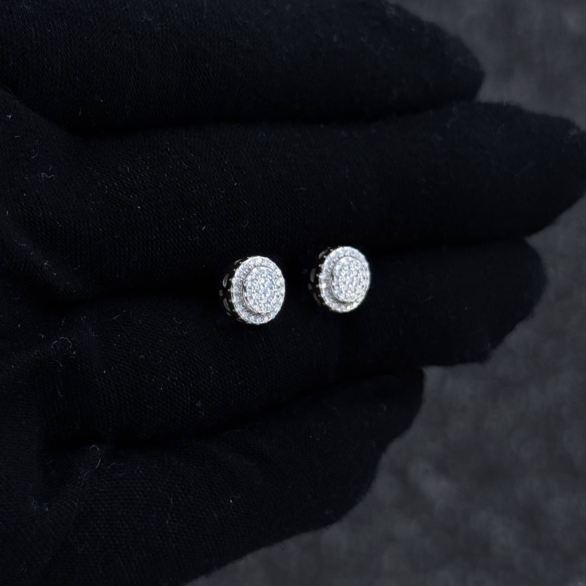 Sterling silver round moissanite cluster earrings displayed on black glove with double halo shine.