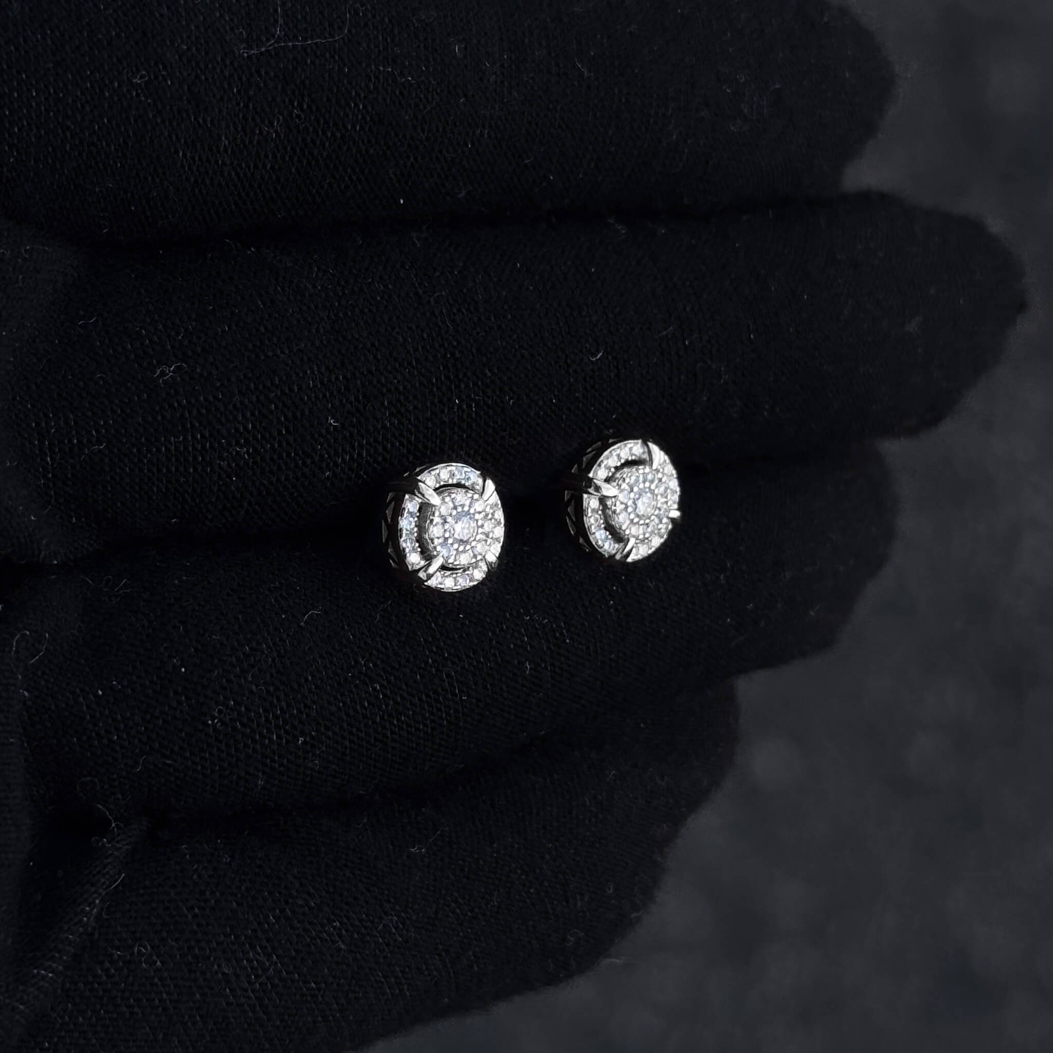 Silver halo moissanite cluster earrings displayed on black glove with sparkling diamond center.