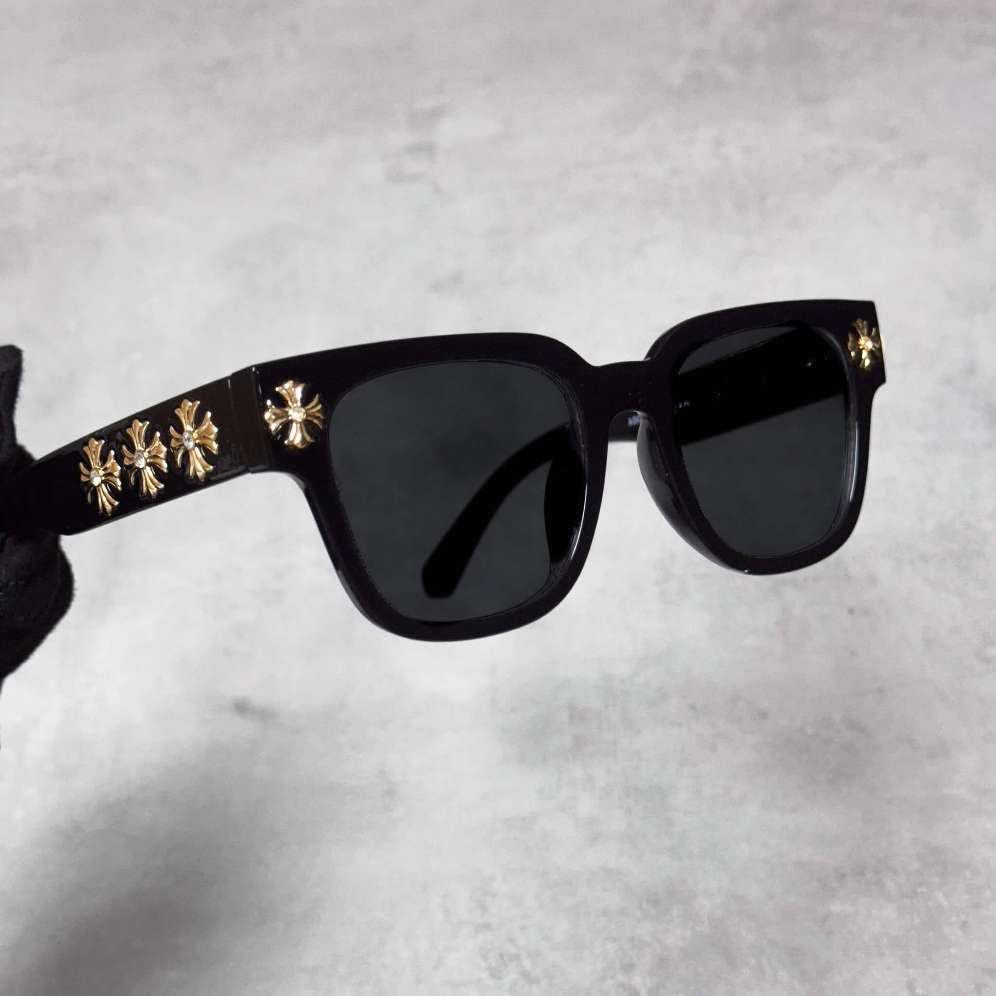 Side angle of black Cross Chrome Inspired Sunglasses with gold cross trim along the temple arms.