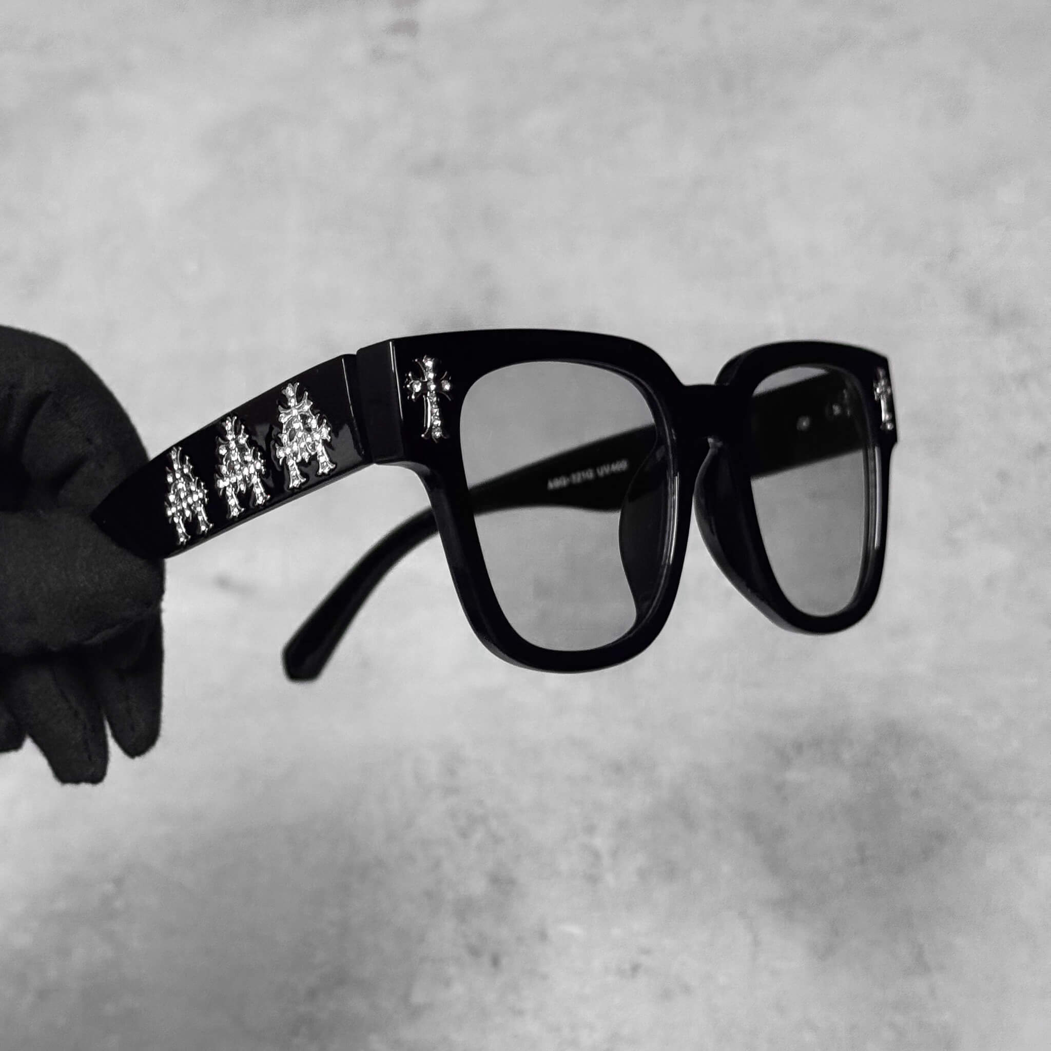 Angled view of smoke-lens Triple Cross Chrome Inspired Sunglasses with silver triple-cross details.