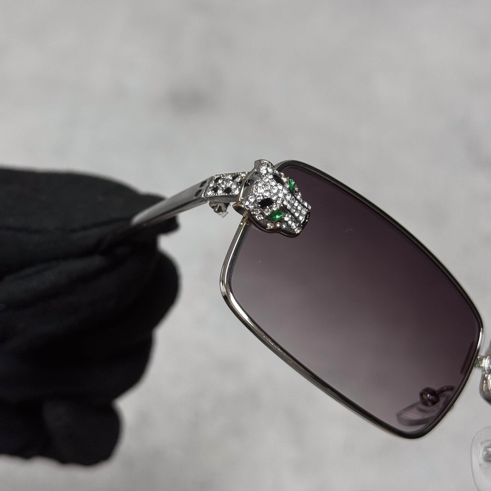 Close-up of silver panther centerpiece on Iced Out Panther Sunglasses with smoke lenses.