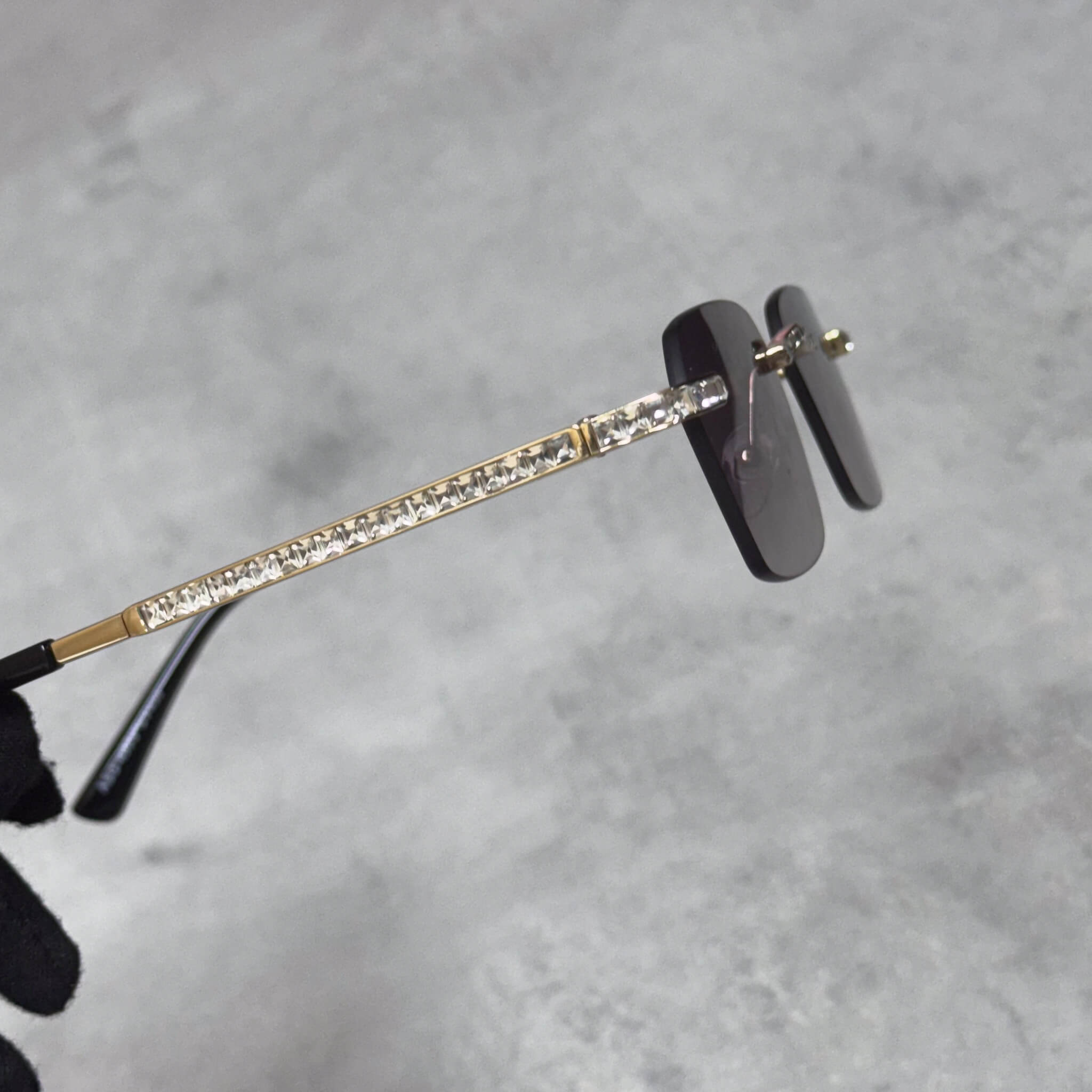 Close-up of gold Baguette Stone Sunglasses showcasing crystal baguette arms and smoke lens design.
