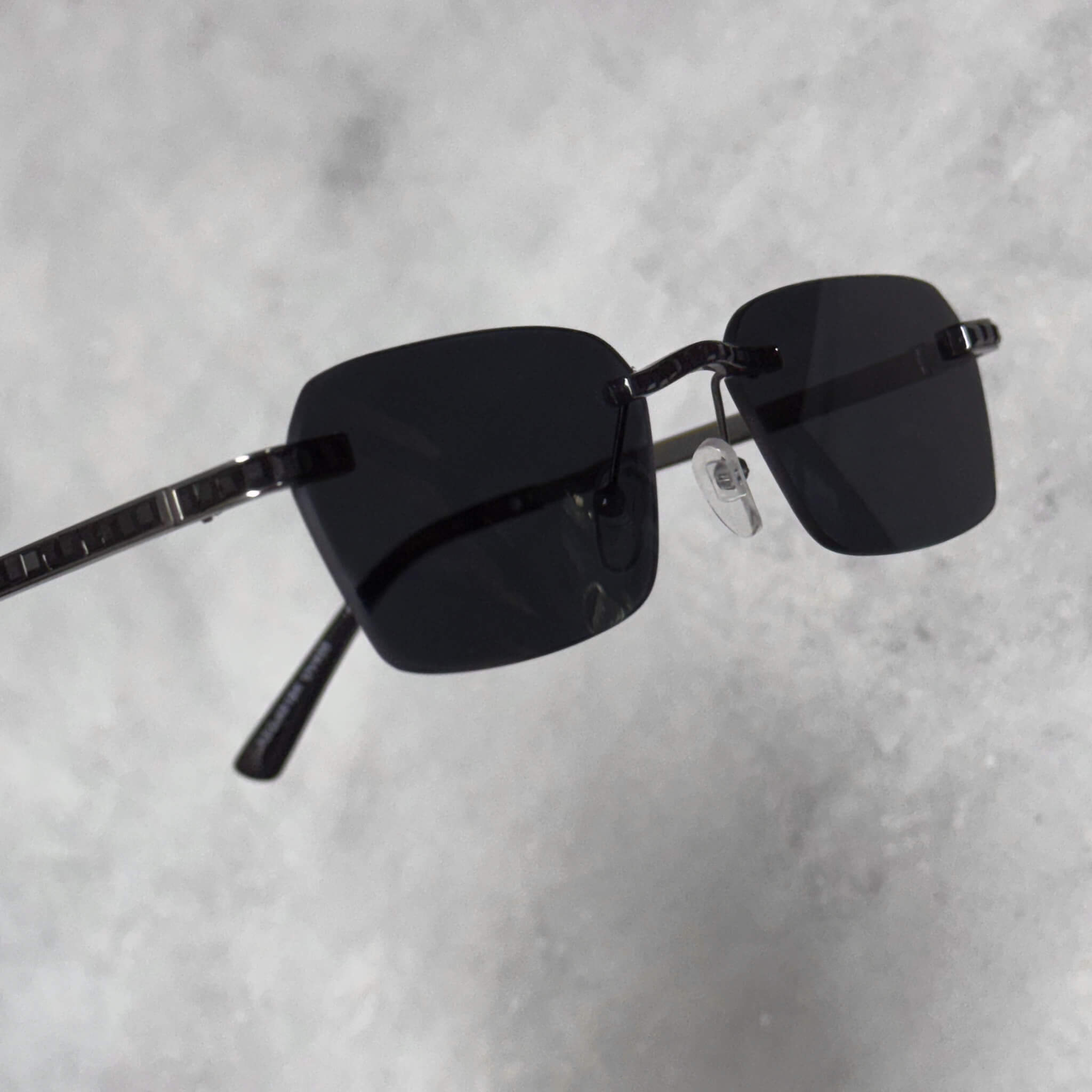 Rimless black lens baguette stone sunglasses shown angled to highlight sleek black frame.
