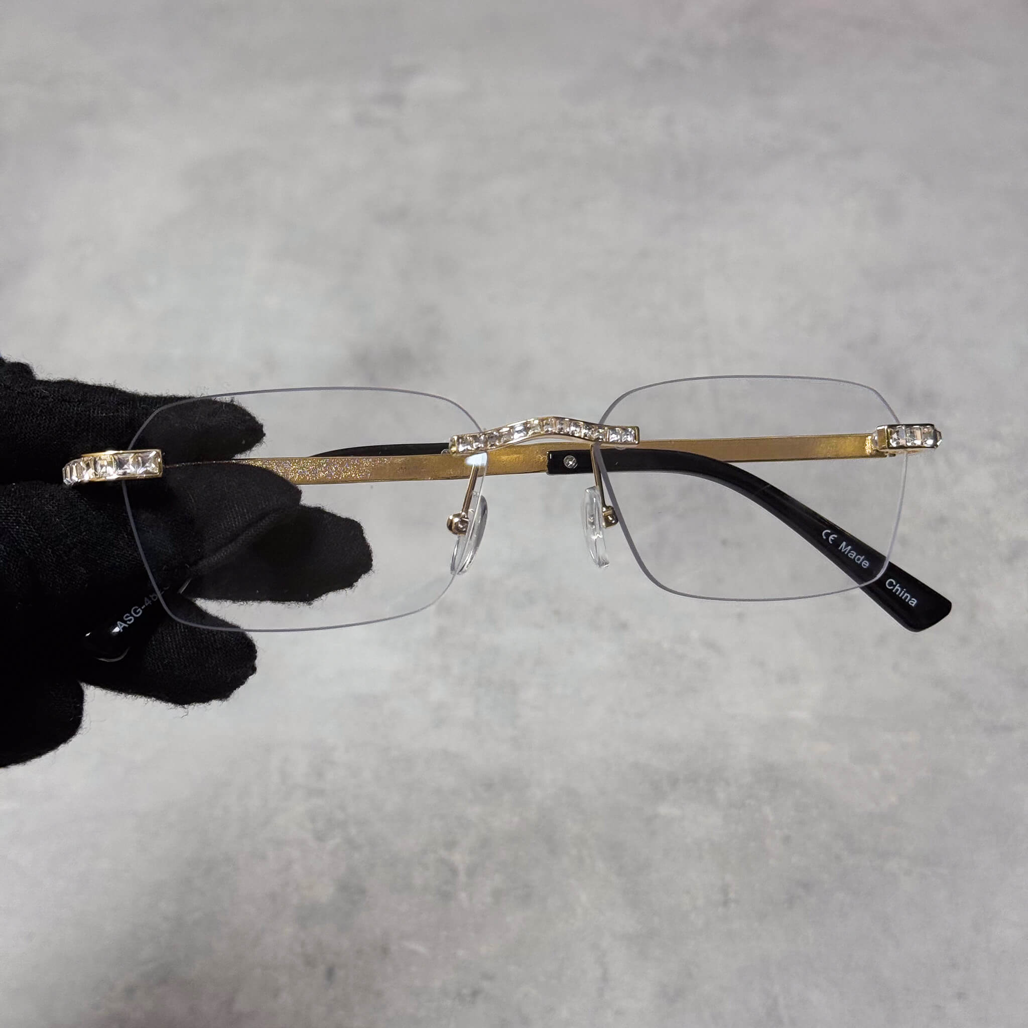 Gold frame clear lens sunglasses featuring baguette stone accents and rimless square design.