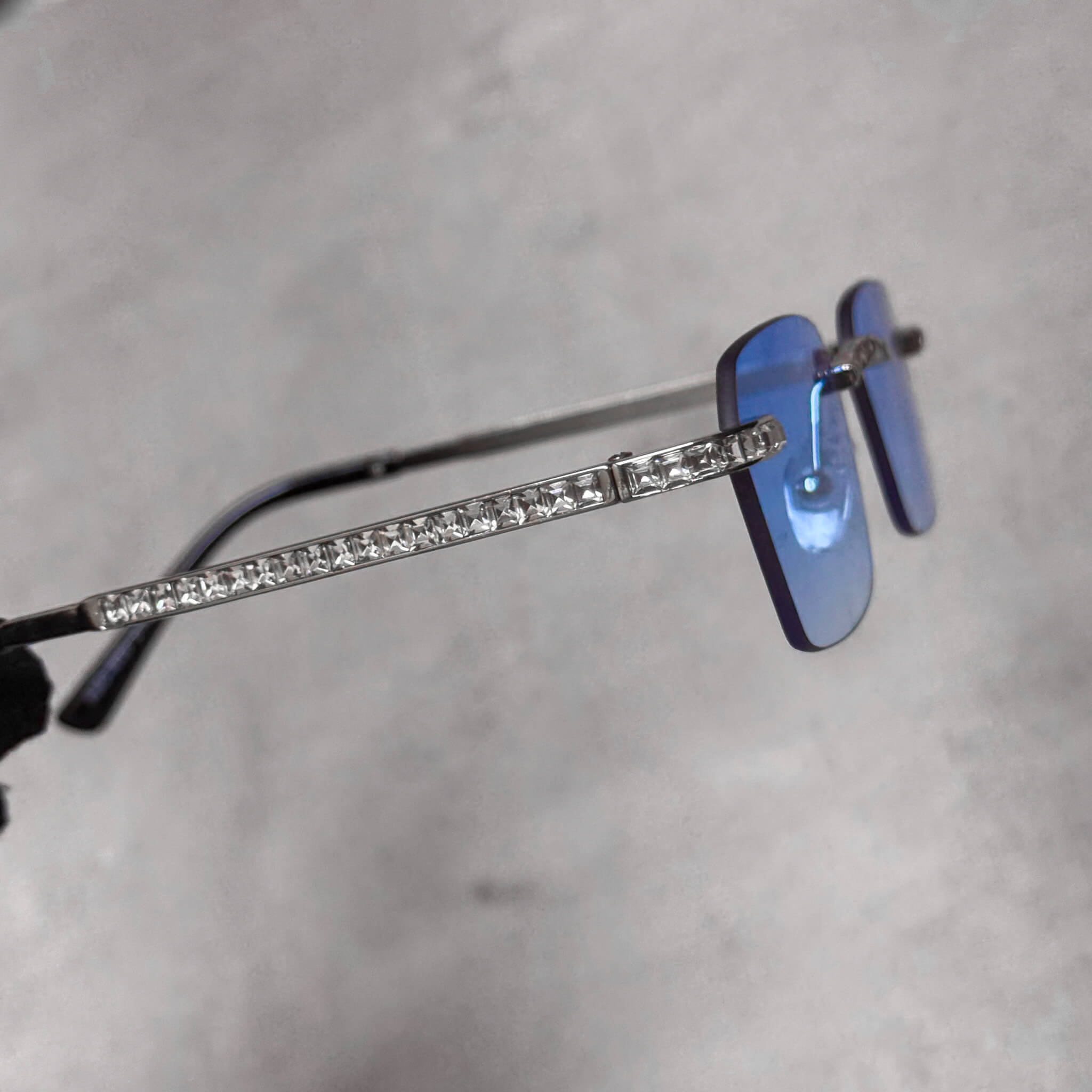 Side view of Baguette Stone Sunglasses featuring blue lenses and silver baguette crystal arms.