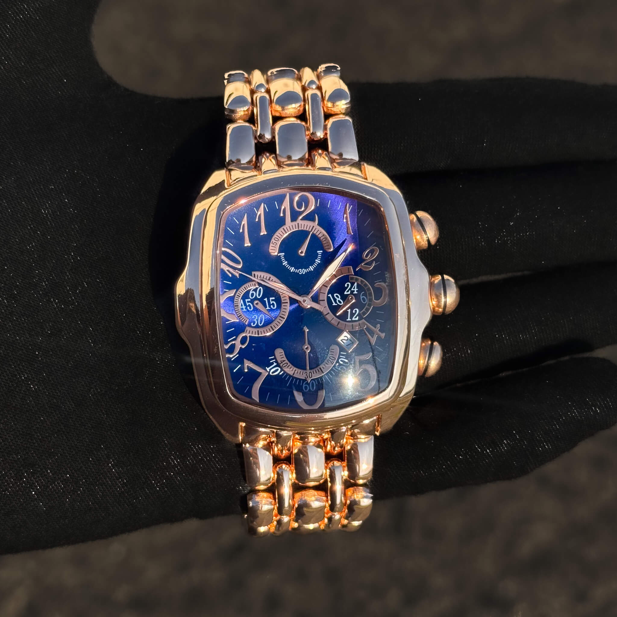 Men’s 43mm Tonneau Watch in rose gold tone with blue dial, bold numerals and metal band.