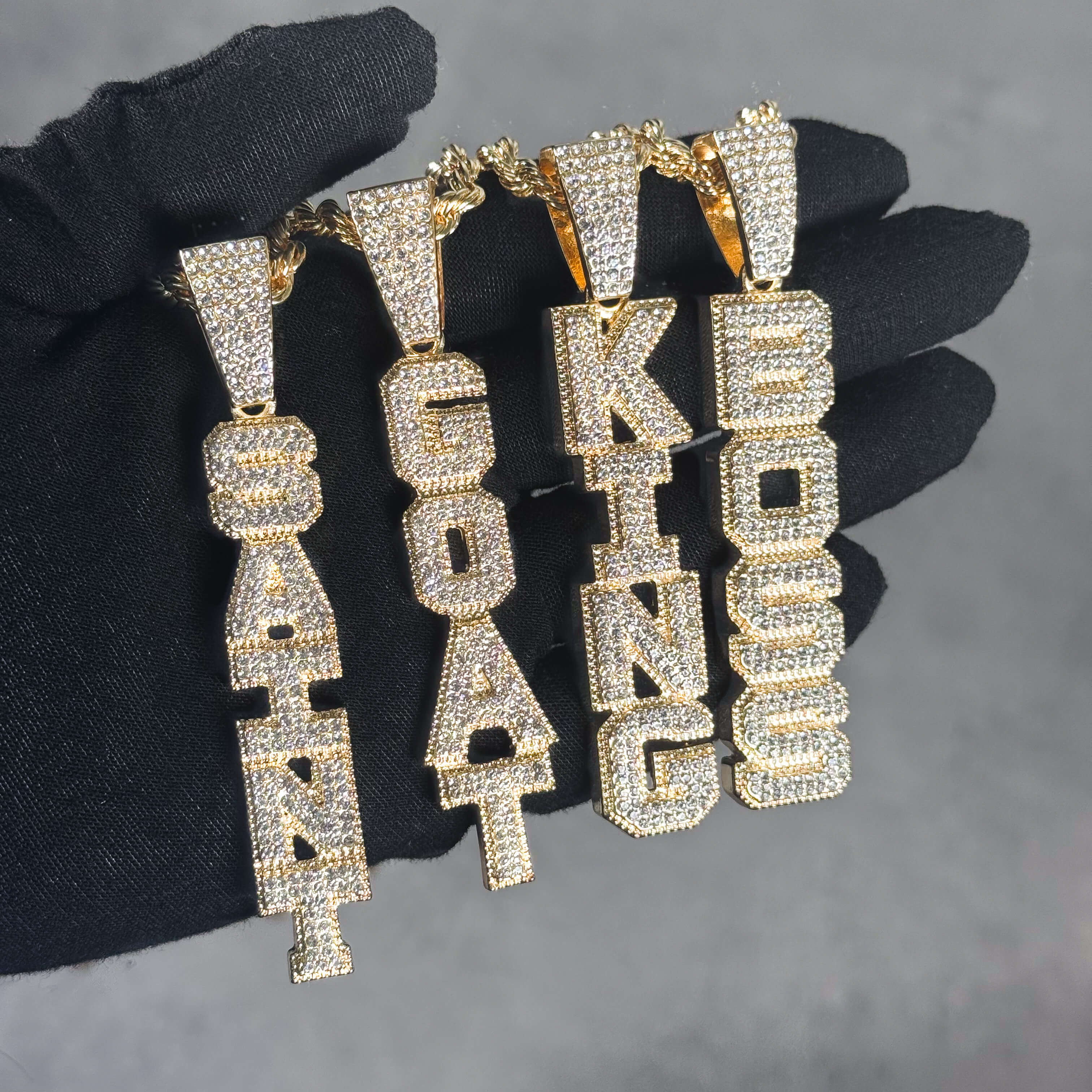 Iced out Vertical Pendant collection with gold CZ letter pendants displayed together.