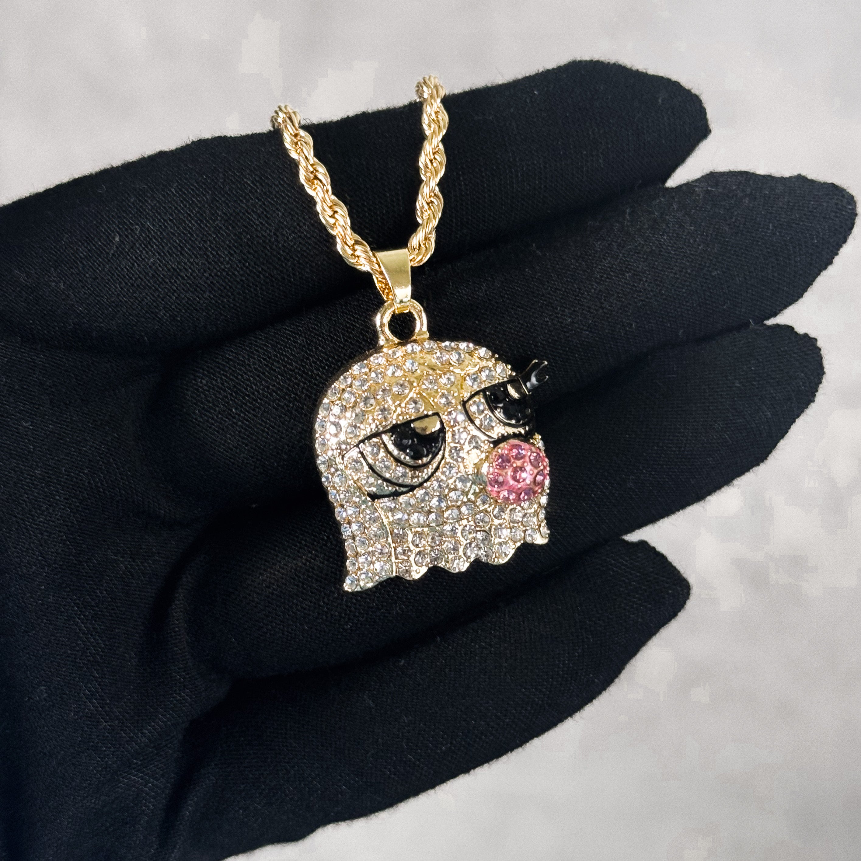 Mini Iced Out Bubble Blowing Doll Pendant worn on hand, gold tone with iced detailing.