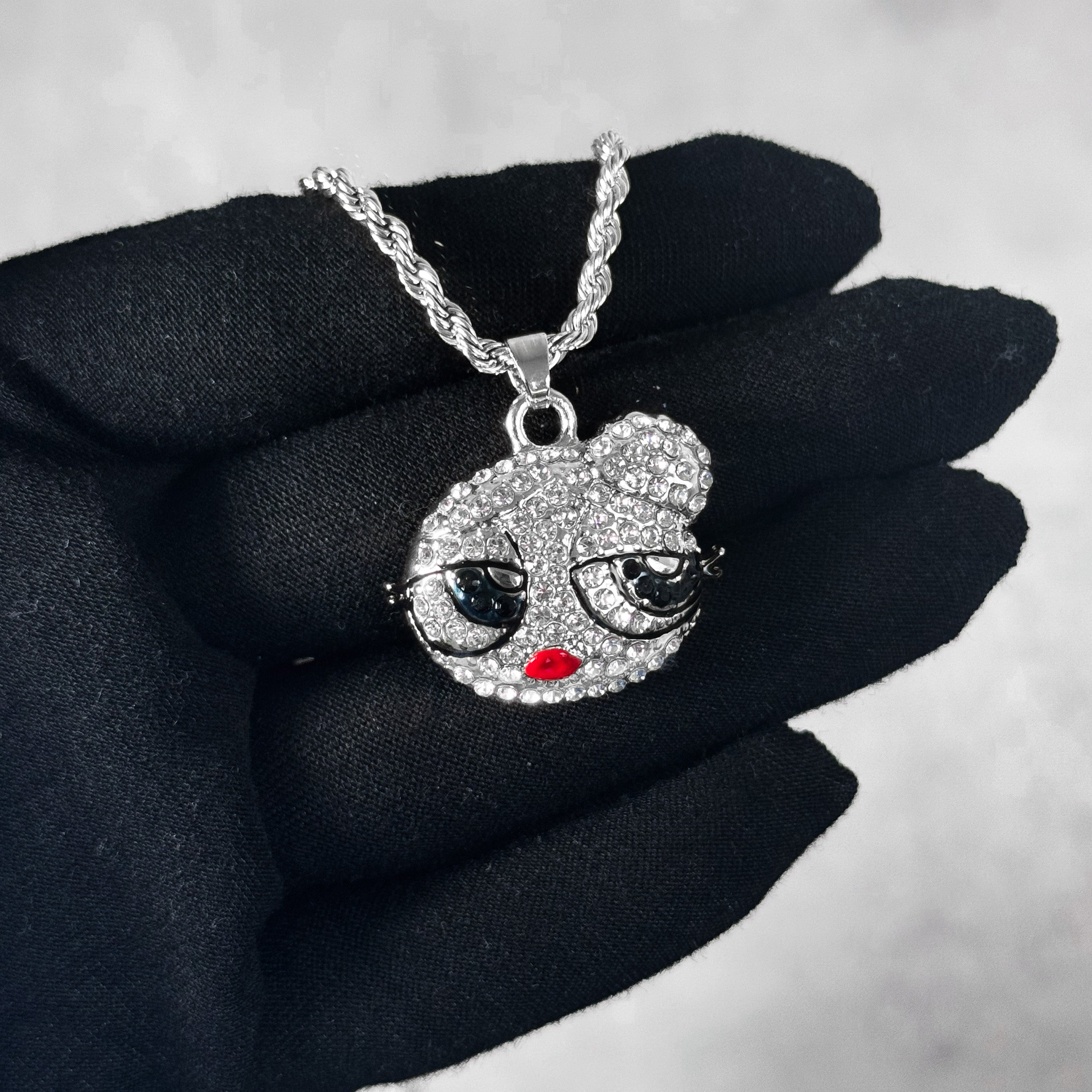 Mini Iced Out Hair Bun Doll Pendant in silver finish with rhinestone details, displayed on hand.