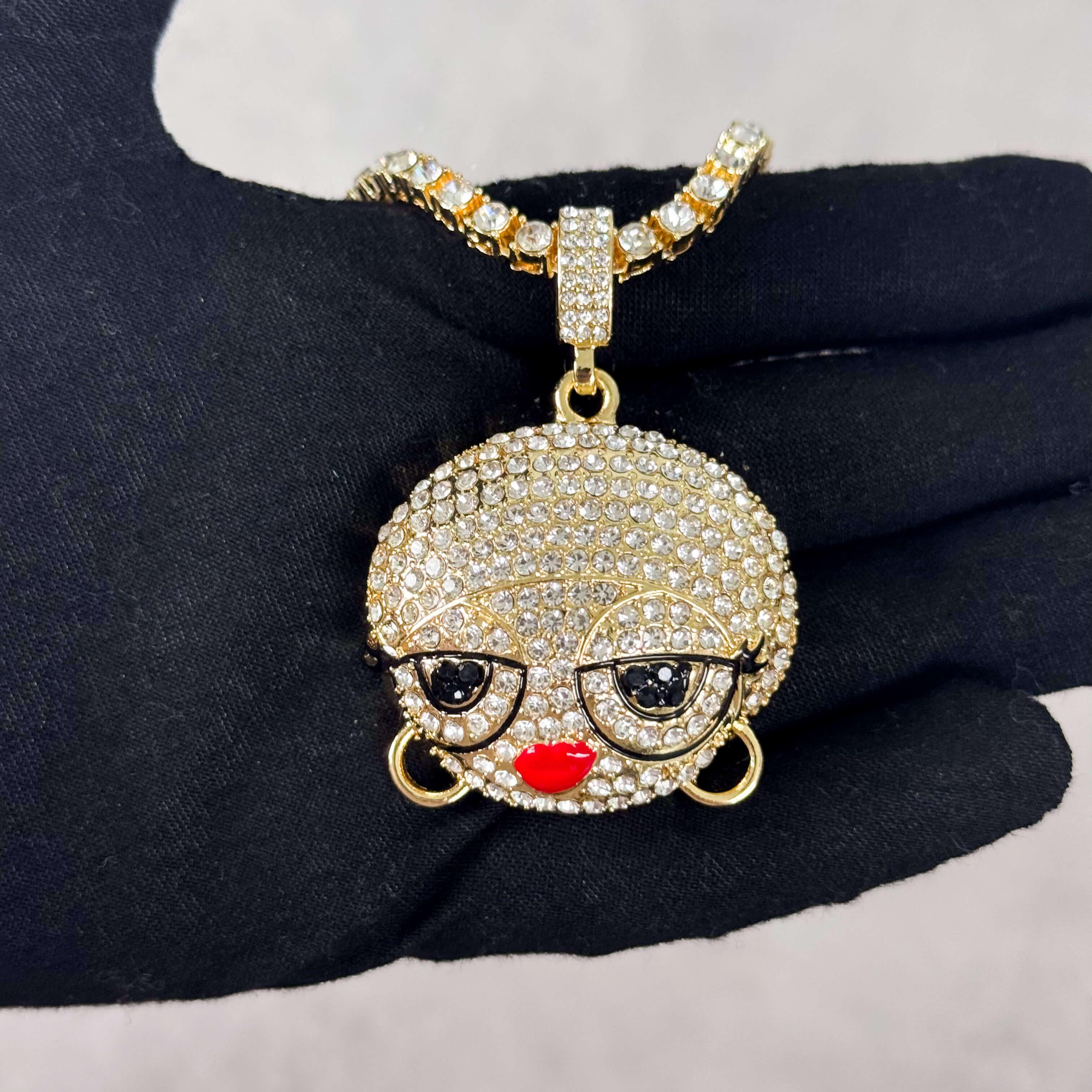 Gold Iced Out Diva Doll Pendant with Tennis Chain held in hand, pavé CZ stones and glasses.