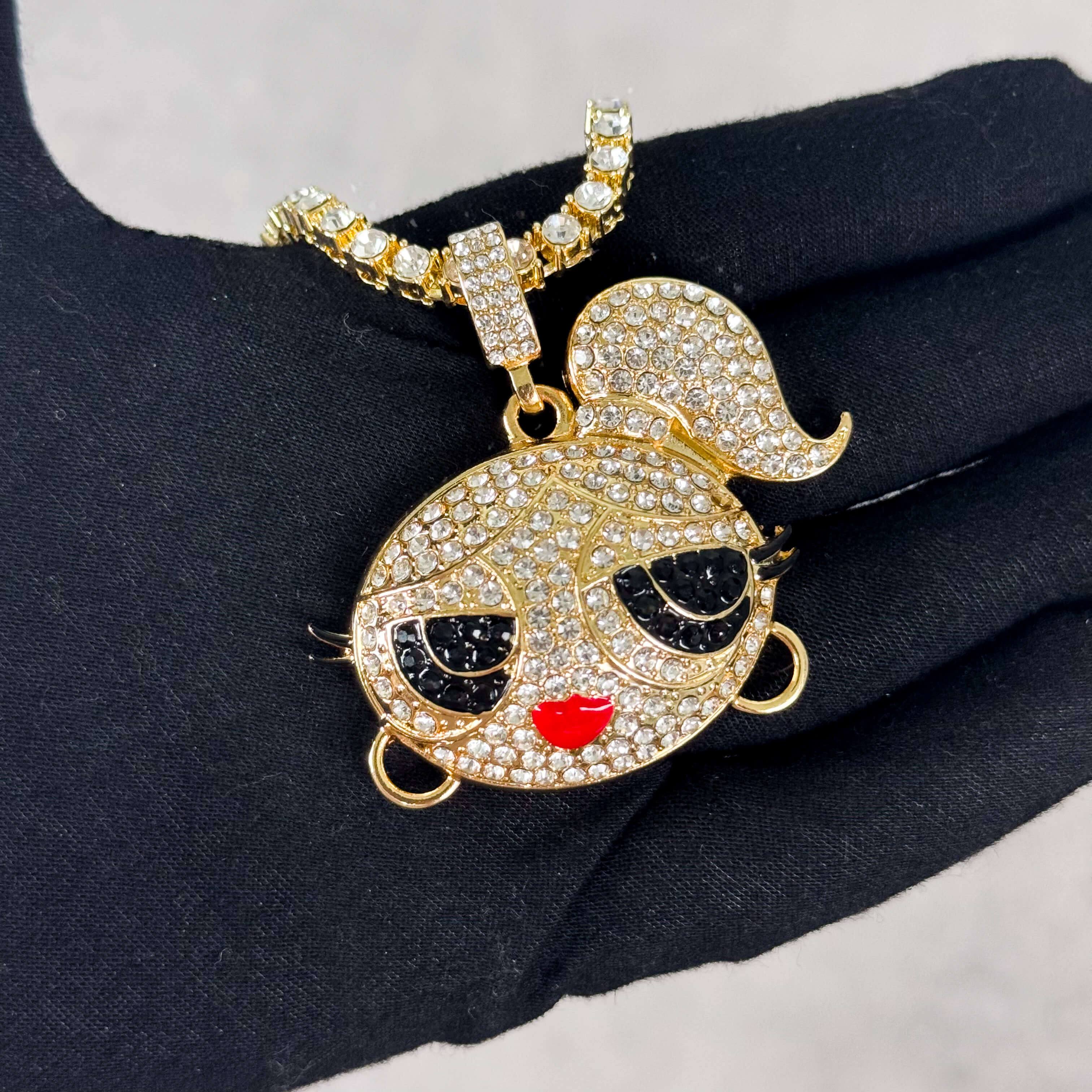 Gold Iced Out Ponytail Doll Pendant with Tennis Chain held in hand, pavé CZ stones.