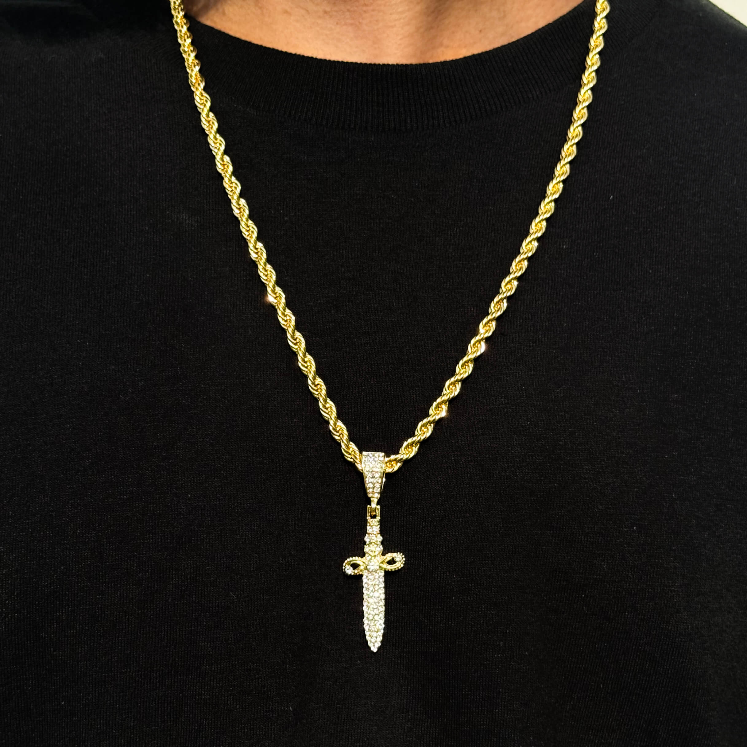 Gold Men's Iced Out Knife Pendant with 4mm Rope Necklace featuring crystal details on black shirt.