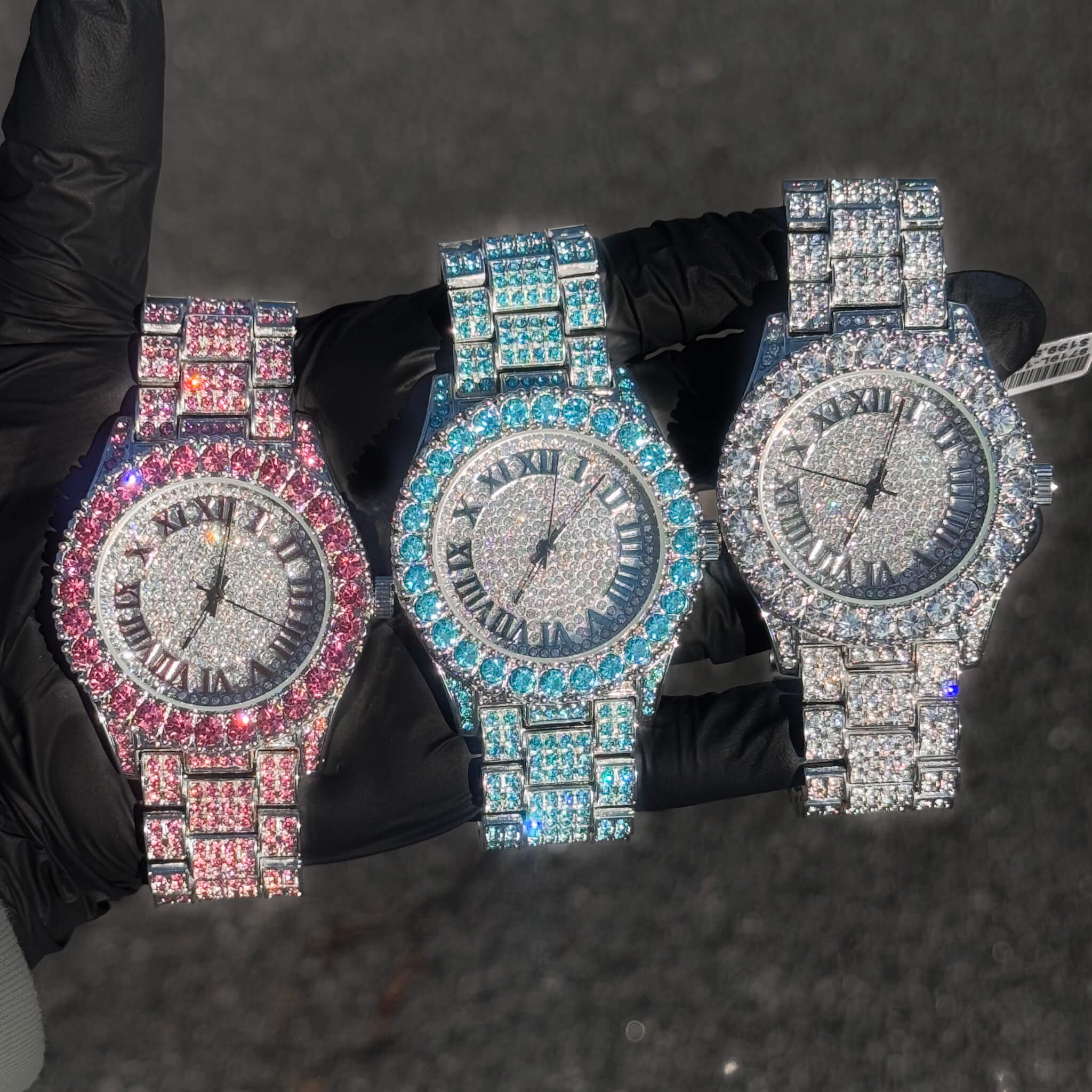Pink, blue, and silver 44mm women’s diamond watches with iced Roman round dials and quartz movement.